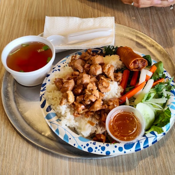 BaoBao Kitchen's Vietnamese dish with chicken, rice, egg roll, vegetables, soup, and sauce.