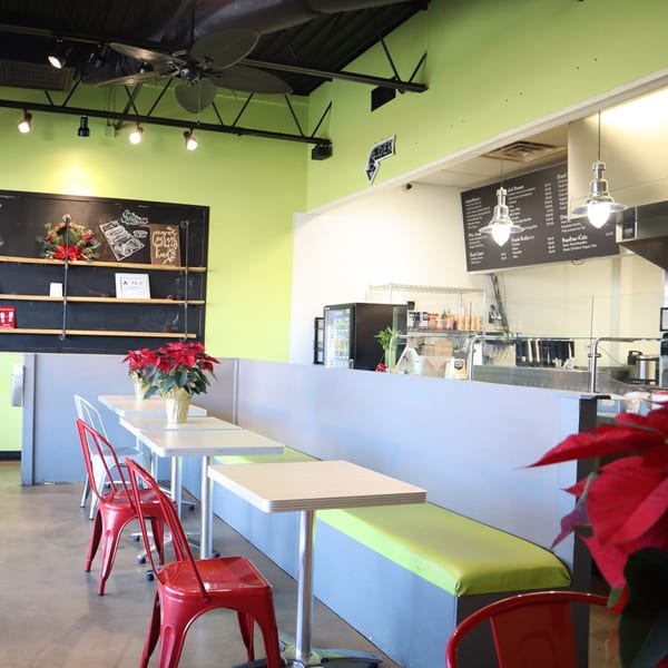 Interior of BaoBao Kitchen with lime green walls, red chairs, and a counter with menu boards.